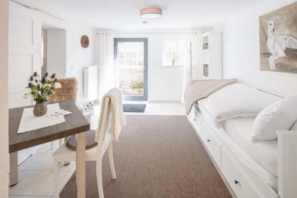 a white bedroom with a desk and a bed at Tiny Ferienwohnung am Stadtpark in Schwäbisch Hall