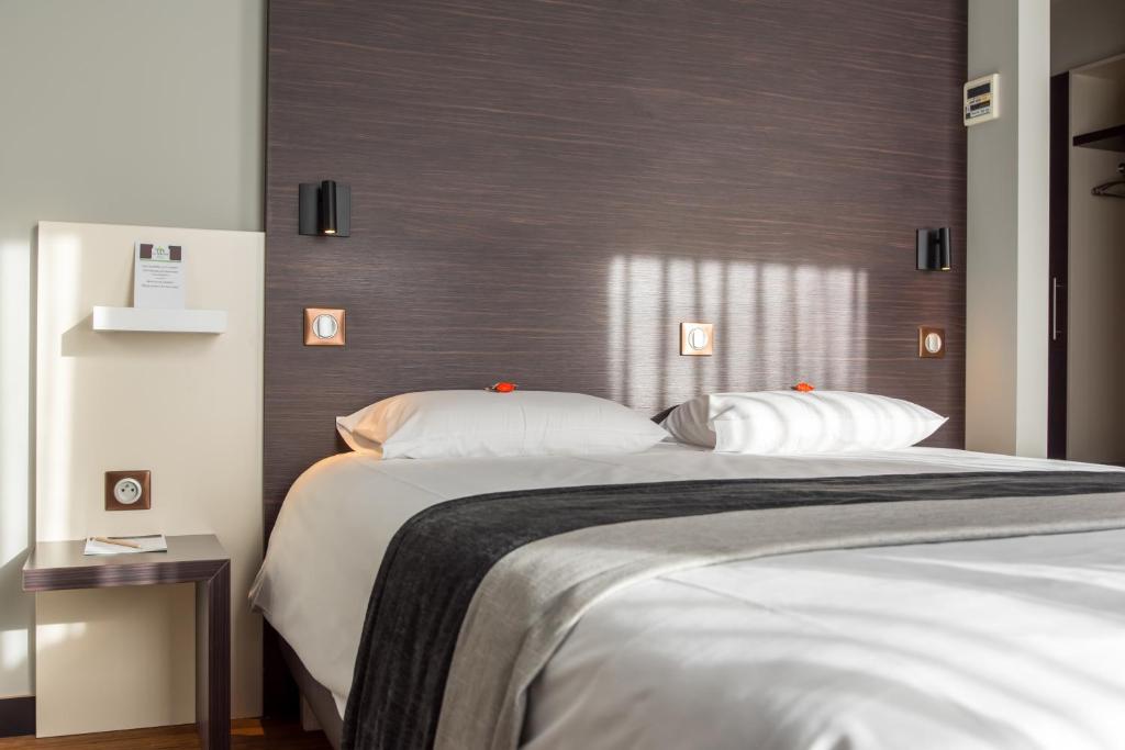 een slaapkamer met een groot bed met 2 kussens bij Le Merceny Motel in Bastenaken