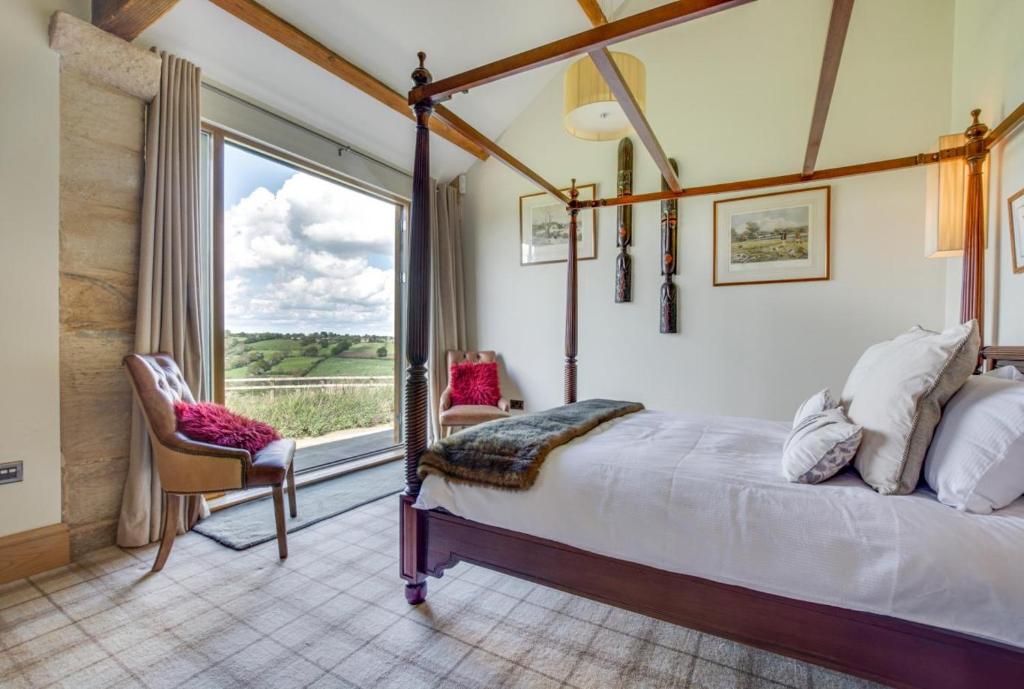 a bedroom with a canopy bed and a large window at Harrogate Barns in Harrogate