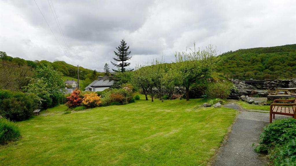 um jardim relvado com um banco e uma casa em Bryn Llys Uchaf em Capel-Curig