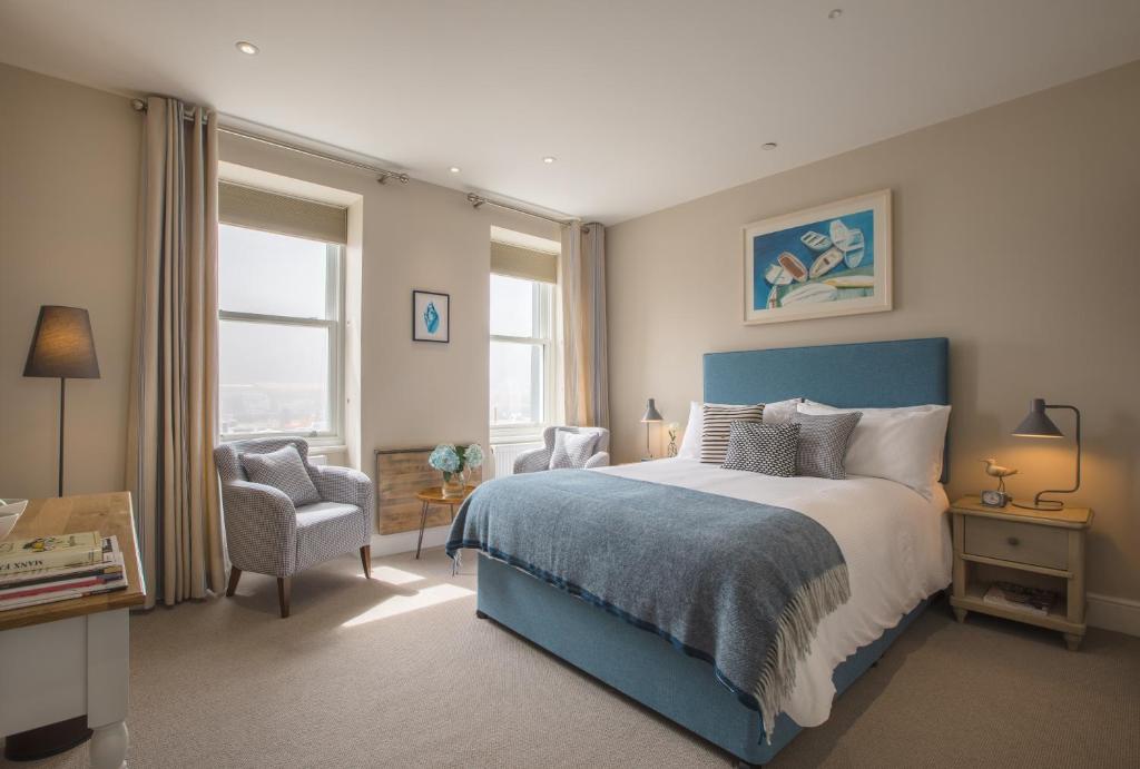 a bedroom with a blue bed and a chair at Sail Lofts in Douglas