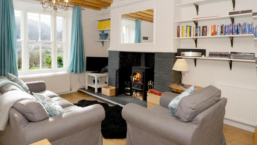 a living room with two couches and a fireplace at One Bron Derw in Dolwyddelan