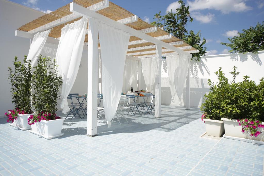 a white pergola with tables and chairs on a patio at Petra Solis in San Pietro in Bevagna