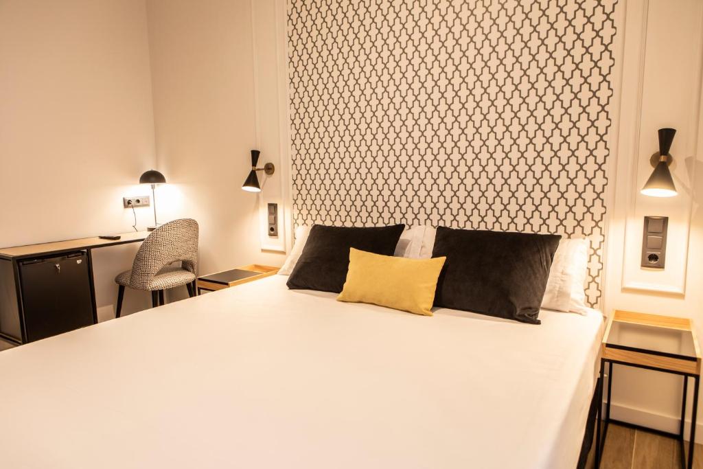 una camera da letto con un letto bianco con due cuscini sopra di Blanq Comedias a Valencia