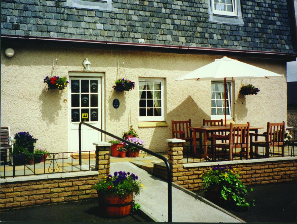 une maison avec une table, des chaises et un parasol dans l'établissement Aaron Glen Guest House, à Loanhead