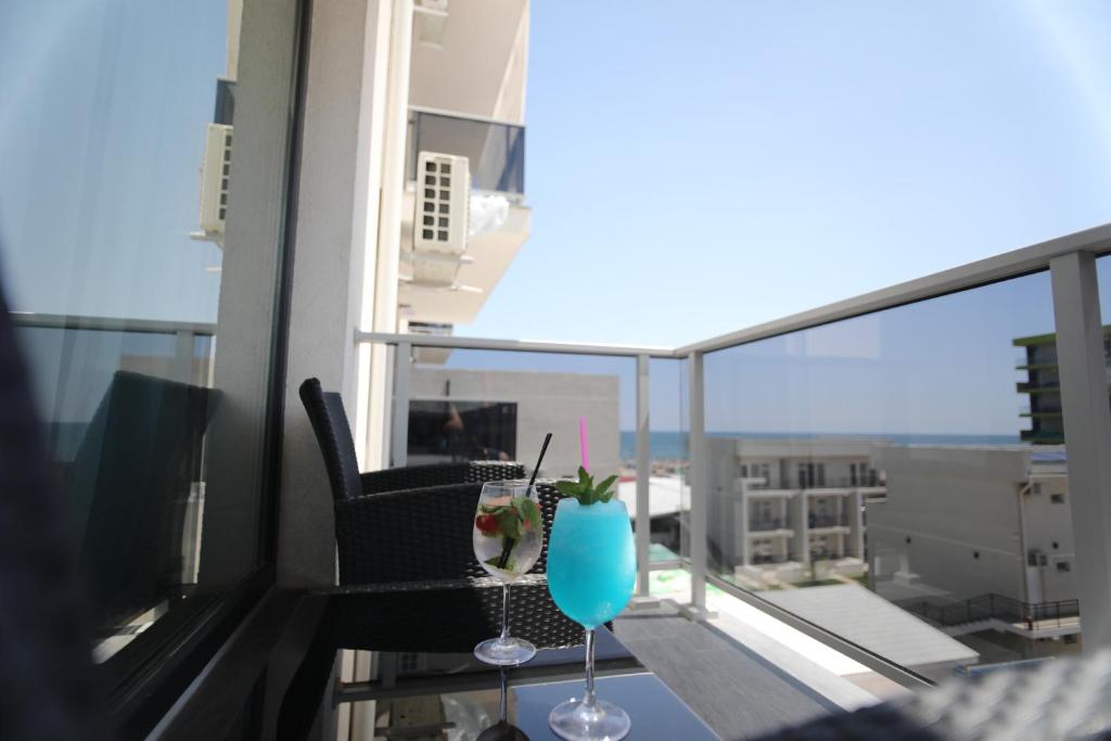 een balkon met een stoel en een drankje op een tafel bij Sammos Black Sea Apartments in Mamaia Nord – Năvodari