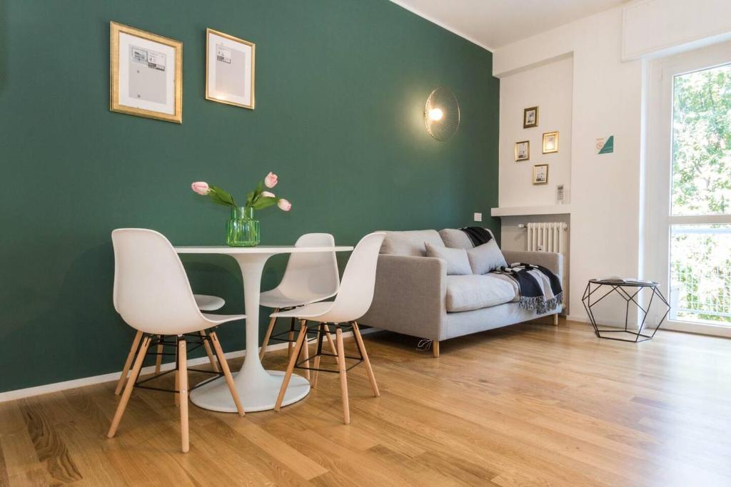 een woonkamer met een tafel en stoelen en een bank bij ALTIDO Fresh Family Apt for 5 near City Life in Milaan