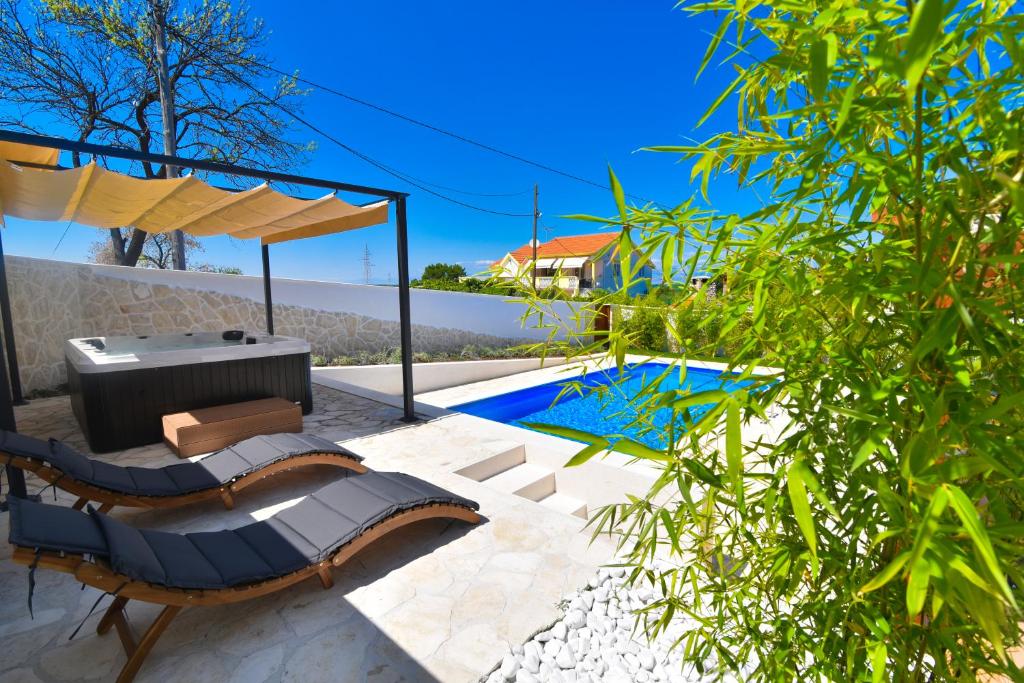 een patio met een bank, een tafel en een zwembad bij Villa Village Idylle with heated pool, sauna, jacuzzy and private parking in Sukošan