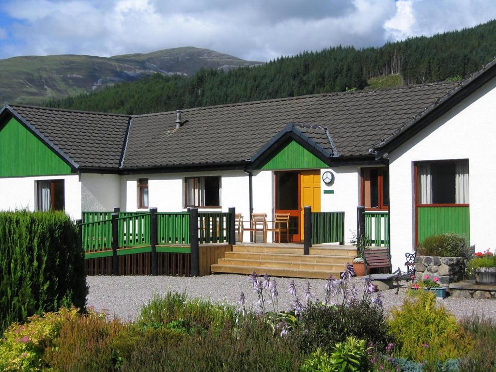 ein weißes Haus mit grünen und gelben Türen in der Unterkunft Cherry Tree Cottage in Glencoe