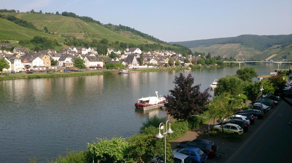 a boat in a river with cars parked next to a town at Mosel View in Zell an der Mosel