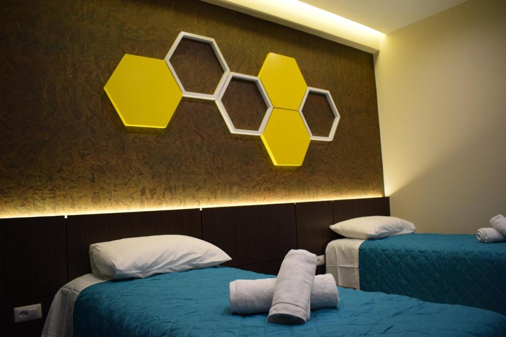 Habitación con 2 camas y pared con panales de miel. en BluePoint Hotel en Kakavijë