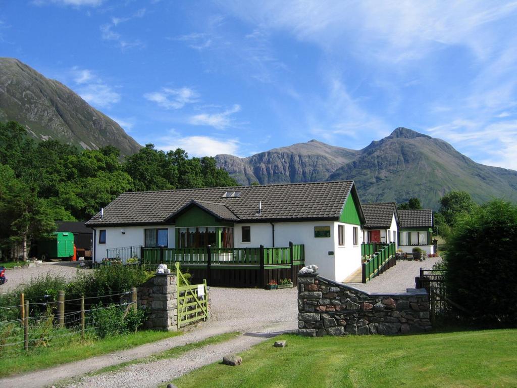 a house with a fence and mountains in the background at Holly Tree Cottage in Glencoe