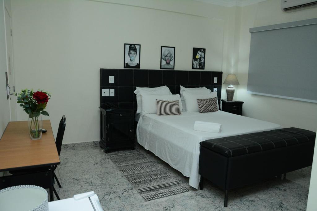 a bedroom with a large bed and a black chair at Hotel Flor de Minas in Uberaba