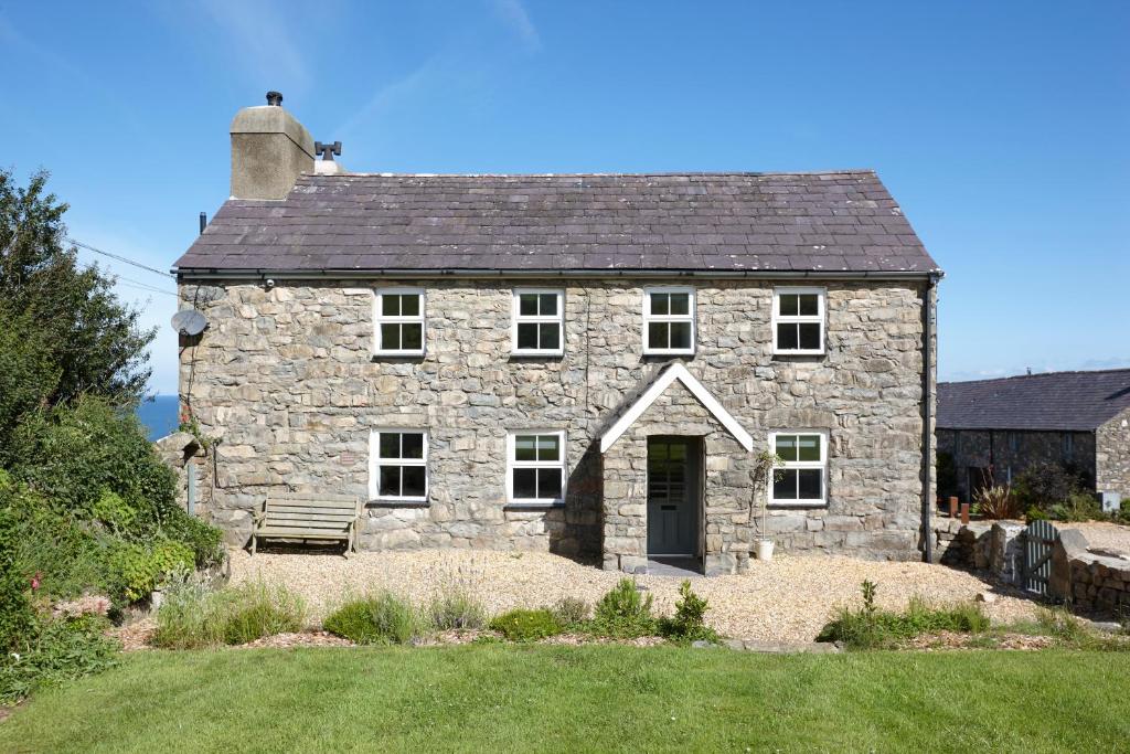 an old stone house with a black roof at The Farmhouse Llyn Peninsula in Pistyll