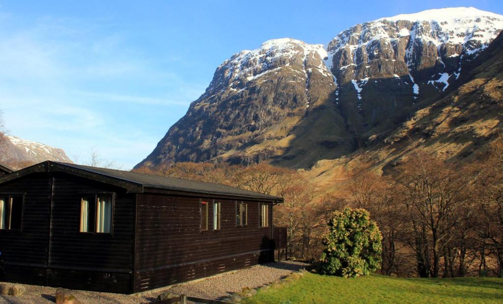 eine Hütte vor einem Berg mit Schnee in der Unterkunft Rowan Tree Lodge in Glencoe