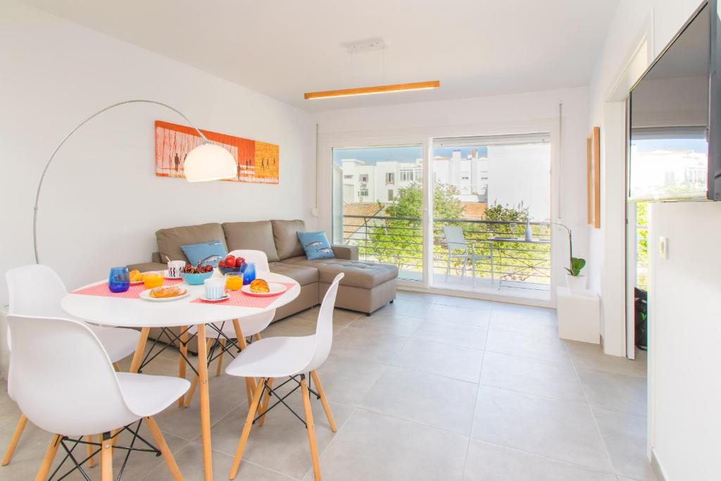 - un salon avec une table, des chaises et un canapé dans l'établissement Apartamento LAUET beach Pollensa, à Port de Pollença
