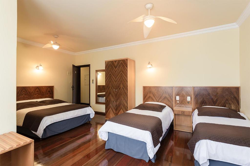 a hotel room with two beds and a ceiling fan at Boroni Palace Hotel in Ouro Preto
