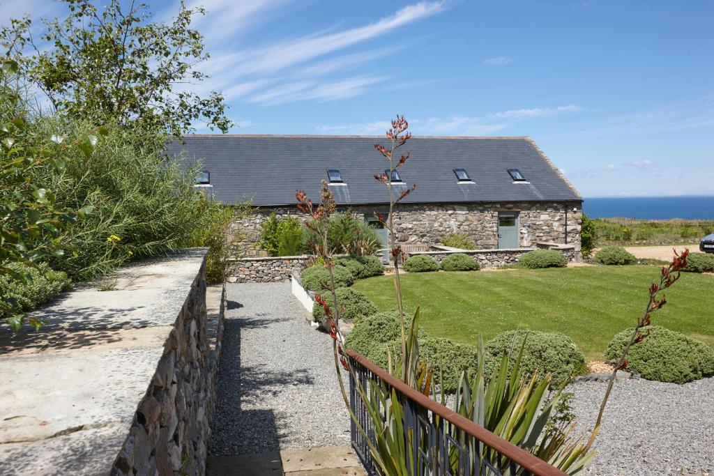 ein Haus mit einem Zaun vor einem Hof in der Unterkunft The Stables 2 - Llyn Peninsula in Nefyn