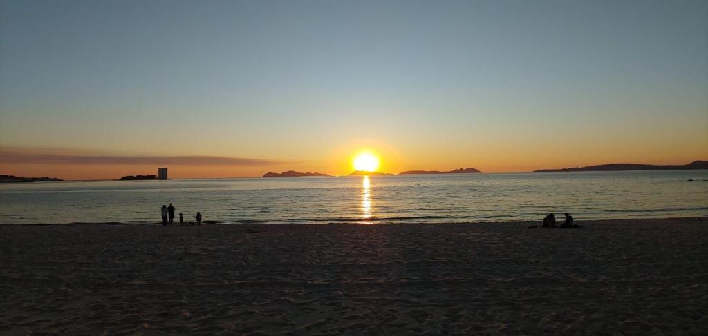 un gruppo di persone sulla spiaggia al tramonto di Apartamento Dreams a Vigo