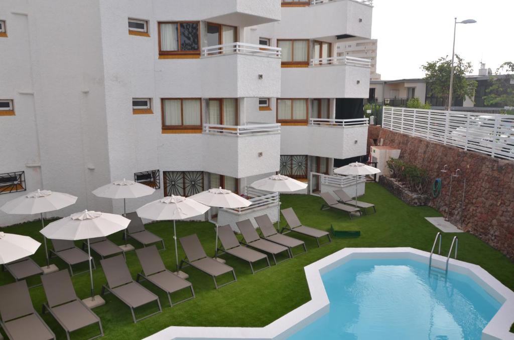 a balcony with tables and umbrellas and a swimming pool at Alsol Datasol in Playa del Ingles