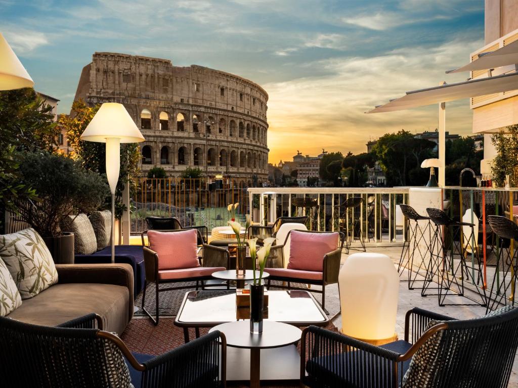 a patio with chairs and tables and the leaning tower at Hotel Palazzo Manfredi – Small Luxury Hotels of the World in Rome