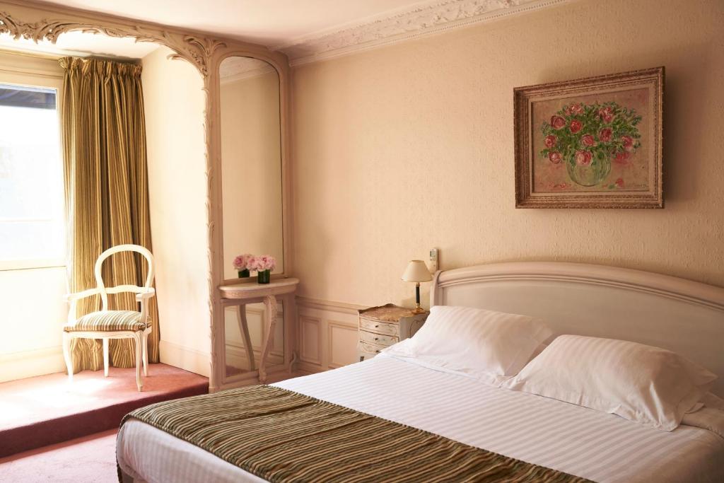 a bedroom with a bed and a chair and a window at Hôtel Langlois in Paris