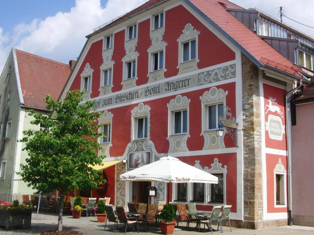 Hotel Angerer في Vilseck: مبنى احمر امامه مظله