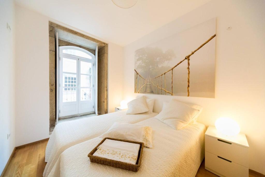 a bedroom with a white bed with a large window at Edifício Portughabit in Viana do Castelo