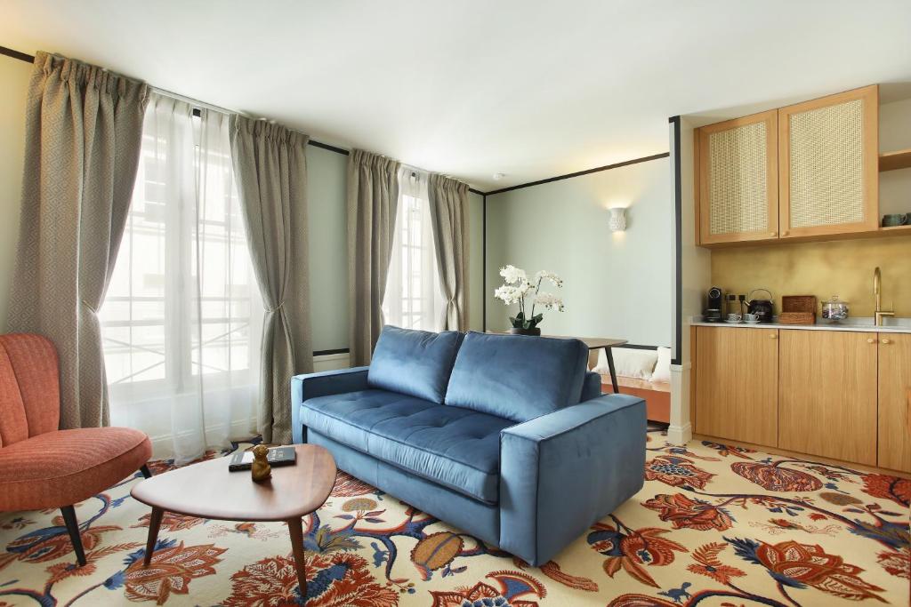 - un salon avec un canapé bleu et une table dans l'établissement Le Ferdinand - Le Marais Serviced Apartments, à Paris