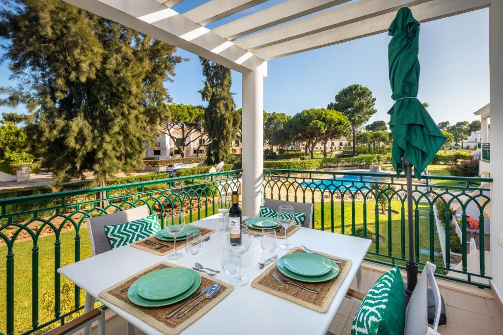a white table with green plates on a balcony at Epic Falésia Apartment by The Portuguese Butler in Olhos de Água