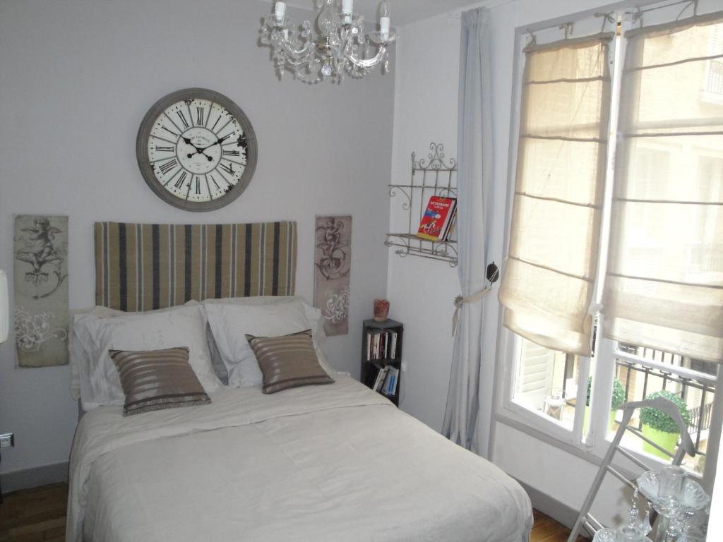 una camera da letto con un letto con un orologio sul muro di Almeria Garden Apartment a Parigi