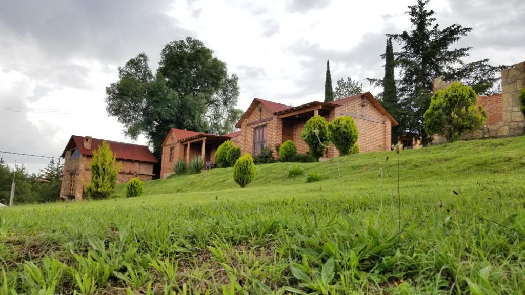 een huis op een grasheuvel met een kerk bij Cabañas villa de San Miguel in Huasca de Ocampo
