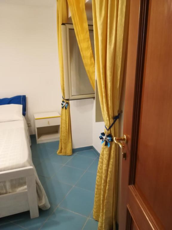 Habitación con cama y puerta con cortinas amarillas. en Stella di Mare, en Santa Maria di Castellabate