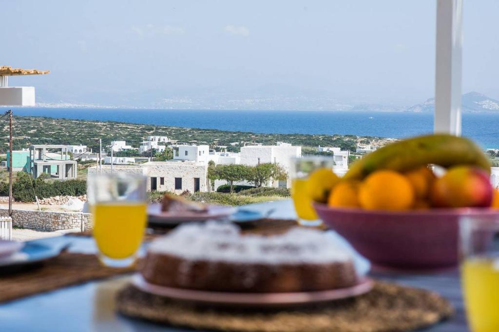 a table with a bowl of fruit and a glass of orange juice at Parian Philoxenia Villa, Santa Maria Beach in Kampos Paros