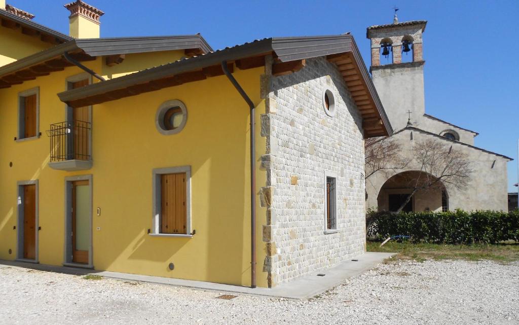 ein gelbes Gebäude mit einem Turm und einer Kirche in der Unterkunft Suite Maria in Buttrio