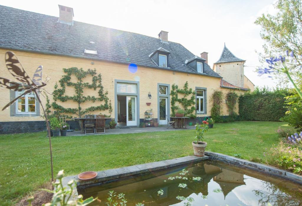 une maison avec un étang dans la cour dans l'établissement B&B Cense de la Tour, à Nil Saint-Vincent