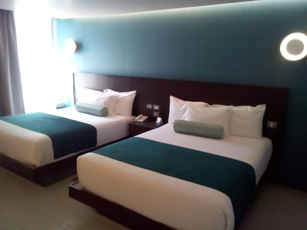 Cette chambre d'hôtel dispose de 2 lits et d'un mur bleu. dans l'établissement Hotel Y Parque Acuático La Caldera, à Villa Abasolo