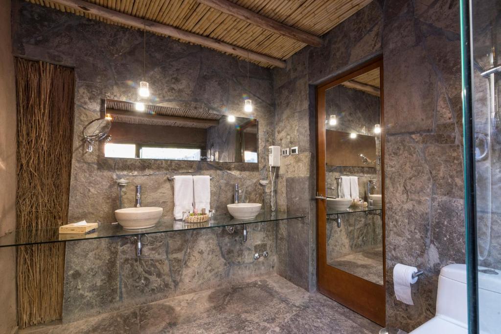 uma casa de banho com 2 lavatórios e uma cabina de duche em vidro. em Hotel Cumbres San Pedro de Atacama em San Pedro de Atacama