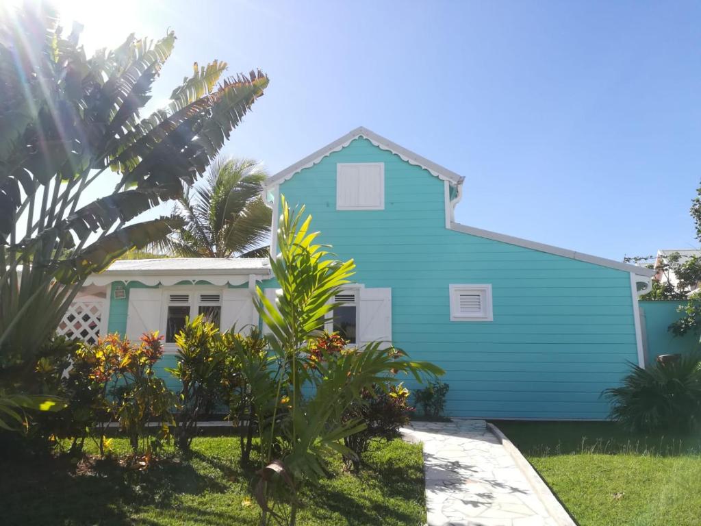 a blue house with palm trees in front of it at Villa Alizé & Villa Aigue-Marine in Sainte-Anne