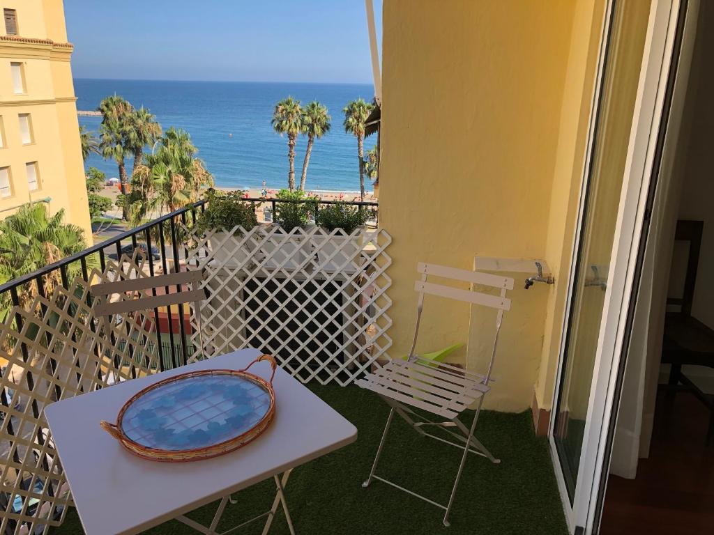 una mesa y una silla en un balcón con vistas al océano en Apartamento Malagueta 1 Linea playa centro Malaga en Málaga