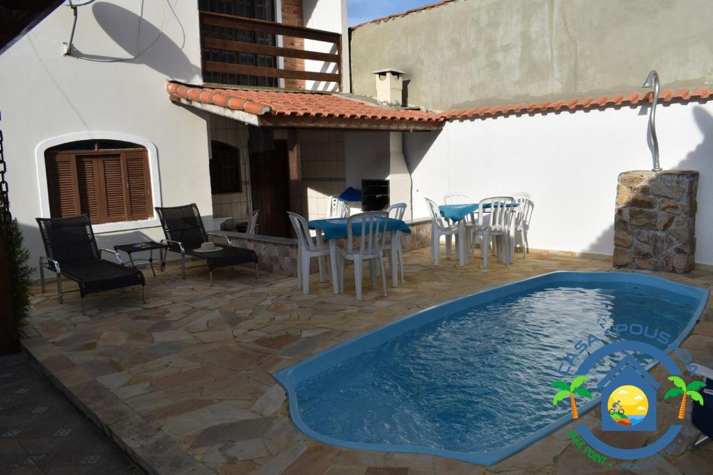 a patio with a swimming pool and a table and chairs at Hostel Bike Point Caraguatatuba in Caraguatatuba