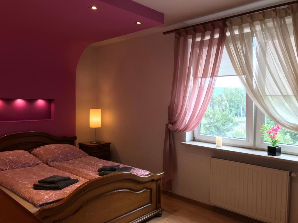 a bedroom with a bed with purple walls and a window at Apartament ''Cleopatra'' z garazem podziemnym, faktury VAT in Kielce