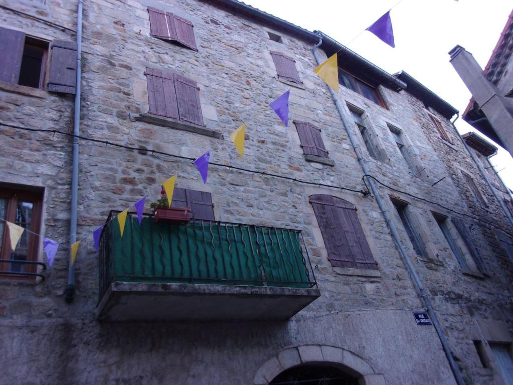 un bâtiment doté d'un balcon verdoyant avec drapeaux. dans l'établissement triplex douillet, à Largentière