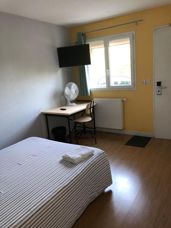 een slaapkamer met een bed, een bureau en een raam bij VILLA HOTEL in Malesherbes