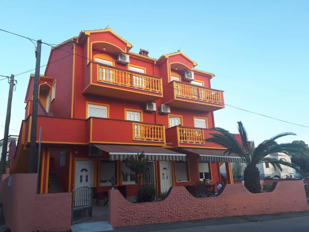 a red building with balconies on the side of it at Apartments Drago in Petrcane
