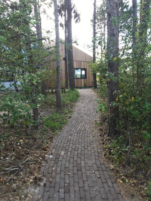 un camino de ladrillo que conduce a un edificio en el bosque en B&B de Getijden en Oost-Vlieland