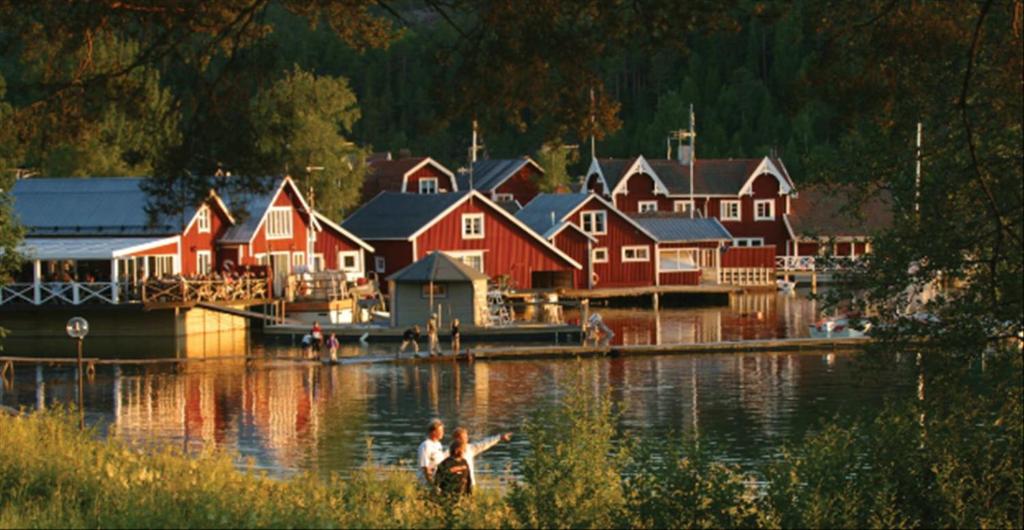 un grupo de casas en un lago con una persona en un barco en Norrfällsvikens Camping, Stugby & Marina en Mjällom