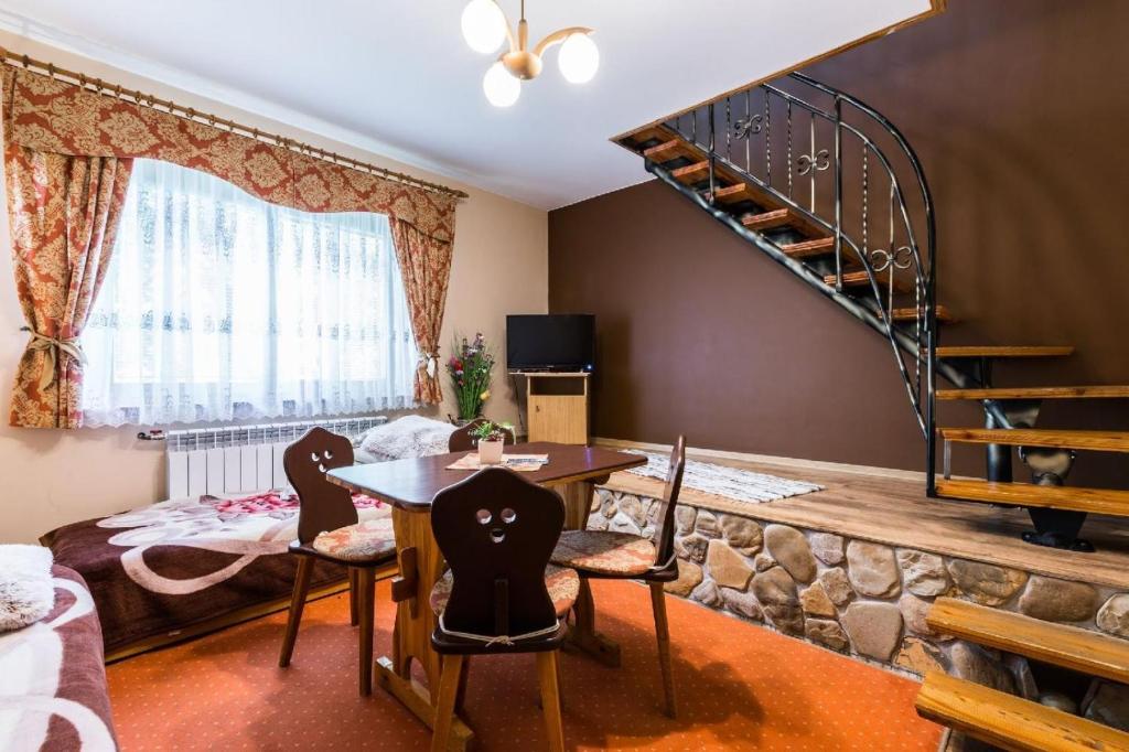 a living room with a table and chairs and a spiral staircase at Willa Cetynka in Zakopane