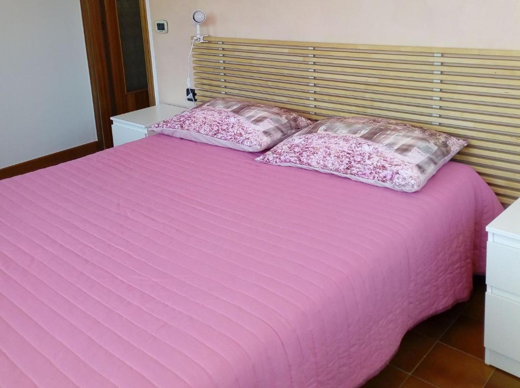 Una cama rosa con dos almohadas encima. en Mansarda a 50 metri dal mare, en Porto SantʼElpidio