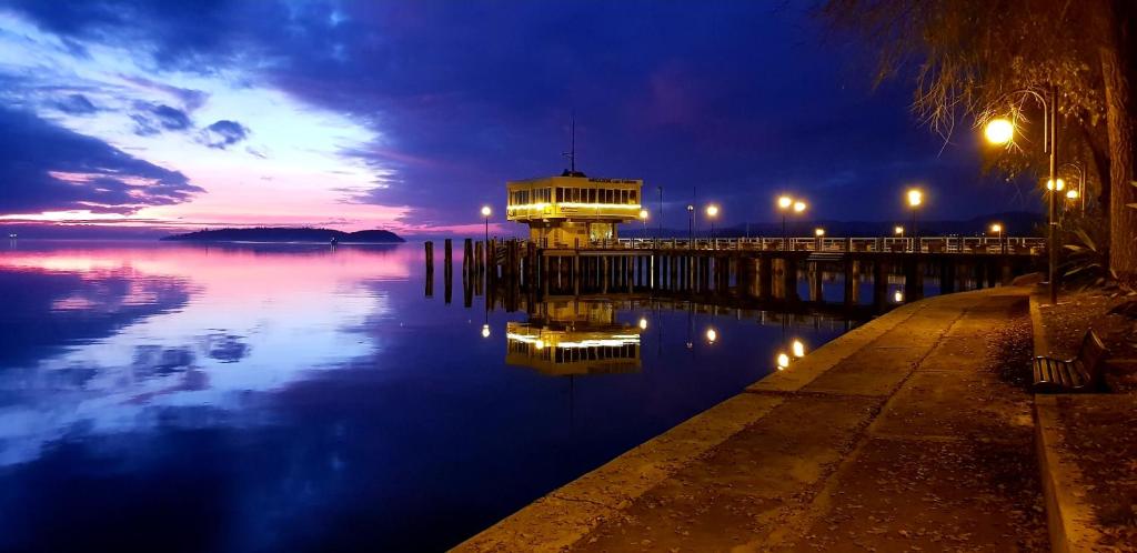 un muelle con un edificio sobre el agua por la noche en Civico36, en Passignano sul Trasimeno